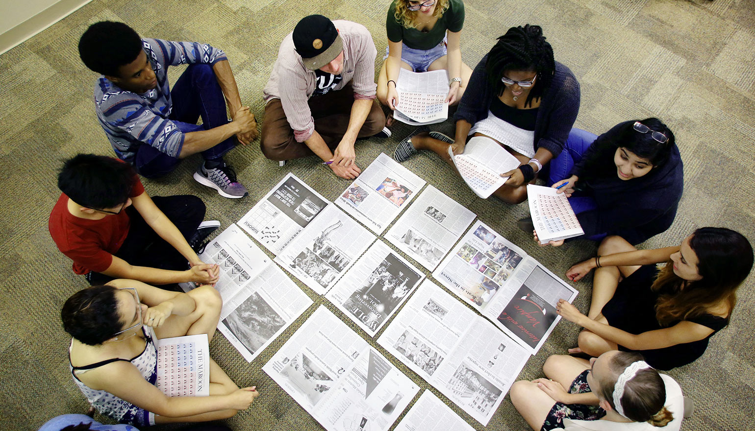 Students surrounding print outs of newspaper draft