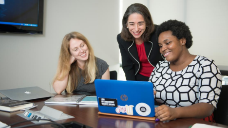 An instructor working with two students at a laptop.